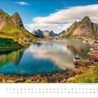 "Juli" zeigt eine ruhige Bucht mit spiegelnden Bergen, Häusern am Ufer und klaren Himmel.