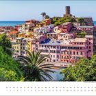 „juli“ steht unter einem Kalender mit bunten Häusern am Küstenhang, umgeben von grünem Laub und Meer im Hintergrund.