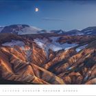 JULI. Eine dramatische Gebirgslandschaft mit bunten Bergen, Schneefeldern und einem aufgehenden Mond am wolkenlosen Himmel.