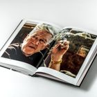 Ein aufgeschlagenes Buch zeigt eine ältere Person, die eine Zigarette raucht. Am Seitenrand steht: "April 2004 in einem Studio in Los Angeles."