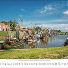 Kalendar: Juli 2023, Grün unterstrichen. Zahlreiche Fischerboote im Hafen, gesäumt von Häusern und grünem Gras unter blauem Himmel.