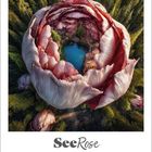 Text: "SeeRose, Juni 2027". 
Riesige, geöffnete Blüte mit einem See in der Mitte, umgeben von Wald.