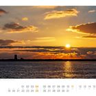 Im Vordergrund: Juli-Kalender. Hintergrund: Sonnenuntergang über dem Meer, Wolken am Himmel, Silhouette einer Insel.