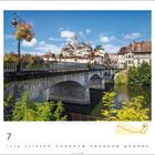Kathedrale Saint-Front de Périgueux, Dordogne. Eine historische Steinbrücke überquert einen Fluss, umgeben von Blättern und Blumen.
