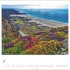 "7" zeigt Juli mit Küstenlandschaft, Felsen, bunten Blumen und Sandstrand, dahinter blaues Meer und Himmel.