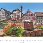 Schiltach, Schwarzwald, Baden-Württemberg. Fachwerkhäuser umgeben einen Brunnen, umgeben von bunten Blumen.