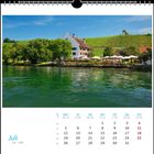 "Juli" steht geschrieben. Ein Fachwerkhaus und grüne Weinberge spiegeln sich im Wasser eines Sees wider.