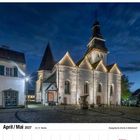 Kalenderdaten April/Mai 2027, Evangelische Kirche in Nümbrecht, abends beleuchtet mit gepflastertem Vorplatz.