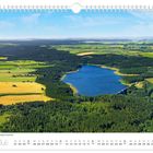 Text: "Blick auf die Talsperre Lehnmühle", "Juli", Kalendertage. Ein Stausee umgeben von Feldern und Wäldern unter blauem Himmel.