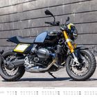"BMW R 12 neunT, Baujahr 2025", ein stilvolles Motorrad vor grauer Betonwand, mit auffälligen gelben Akzenten.