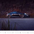 Text: "JULI" und "Porsche 911 GT3 (991.1)". Ein schwarzes Auto auf einer Landstraße, mit felsigem Hintergrund.
