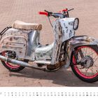 Simson Schwalbe KR51/1 Kalender im Januar, rostiger Motorroller mit rotem Lenker und Rädern auf gepflastertem Boden.