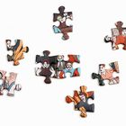 Puzzle-Teile mit bunten Zeichnungen von Menschen in verschiedenen Posen auf weißem Hintergrund verteilt.