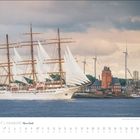 Juli 2027, Hamburg, Kalender. Großes Segelschiff vor einer Hafenkulisse mit Windrädern und einem markanten alten Gebäude.