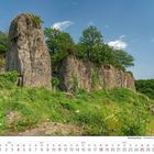 Kalenderseite 7. Juli 2027. Bild von Felsen im Siebengebirge mit üppiger Vegetation und klarem Himmel.