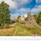 Kalenderblatt Juli 2027. Ruinenweg im Siebengebirge, umgeben von Bäumen und Wiesen unter leicht bewölktem Himmel.