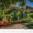 Kalenderseite Juli 2027. Ein charmantes Steinhaus mit grünen Fensterläden, umgeben von blühenden Gärten und Bäumen.