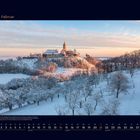 02 Februar. Winterlandschaft mit einer Burg auf einem Hügel umgeben von schneebedeckten Bäumen im Sonnenuntergang.