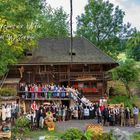 Herzland der Uhren und Wasserfälle. Gruppenbild vor rustikalem Haus, Menschen in traditioneller Kleidung.