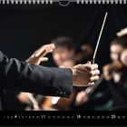 Kalenderblatt: Monat 7, Tage 1-31. Dirigent dirigiert ein Orchester, unscharfe Musiker im Hintergrund.