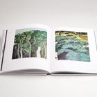 Offenes Buch mit zwei Illustrationen: Links Bäume mit grüner Krone, rechts große grüne Blätter in Landschaft. Seitenzahlen unten.