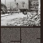 Der Titel lautet "THE HUMANITARIAN GIFT". Bild zeigt zerstörte Gebäude und Trümmer auf einer Straße, mit Menschen darauf.