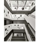 Seite 61. Text: "Daseins- und Lebensraum". Modernes Treppenhaus mit runden Fensterausschnitten und drei Personen auf einer Bank.