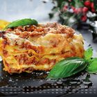 Kalender mit Wochenenden in Weiß. Lasagne-Stück mit Basilikum, im Hintergrund rote Beeren und grüne Blätter.