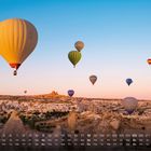 Kalender mit einer Reihe von Tagen, Wochen. Heißluftballons schweben über einer malerischen Landschaft bei Sonnenaufgang.