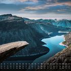Kalender mit Daten und Wochentagen unten. Markante Felsformation ragt über einen tiefen, blauen Fjord.