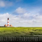 Kalendertext: Wochentage und Zahlen darunter. Ein Leuchtturm steht in einer grünen Landschaft unter blauem Himmel mit Wolken.
