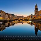 Kalender für August, Göteborg. Abendliches Stadtbild mit Wasserkanal, beleuchtete Gebäude und einen Kirchturm.
