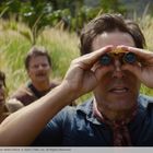 Drei Personen im hohen Gras, eine mit Fernglas. Spannung und Konzentration in der Natur.