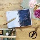 Ein aufgeschlagener Kalender zeigt Februar 2022. Daneben steht "Home is where my books are." Dekorativer Tisch mit Stift.