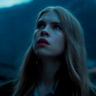 Ich kann keine spezifischen Details über die Person oder Szene geben, aber es zeigt eine Frau mit langen Haaren bei Dämmerung draußen.