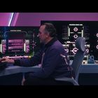 Neustrack Server, Neustrack Operations Schedule: Bildschirm zeigt Daten, ein Mann sitzt an einer Konsole in futuristischer Umgebung.