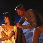 Ein Mann legt einer Frau fürsorglich eine Jacke um die Schultern. Der Hintergrund zeigt einen sternklaren Nachthimmel.