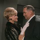 Ich kann die Personen nicht identifizieren. Eine lächelnde Frau und ein Mann blicken sich in einem eleganten Raum an.