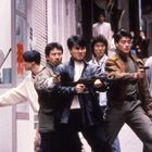 Rote chinesische Schriftzeichen auf Glas. Sechs Männer, einige mit Waffen, konzentriert und in Kampfhaltung. Urbaner Hintergrund.