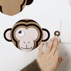 Eine Hand hält einen runden Papier-Ausschnitt neben einem Affen-Gesicht aus Papier.
