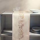 Die Tischdecke zeigt dezente Blumenstickereien. Sie liegt auf einem Metallregal, darauf stehen Gläser und Schalen.