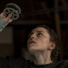 Eine Person betrachtet konzentriert einen alten Filmstreifen, den sie über ihrem Kopf hält.