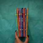 Acht bunte Bücher mit verschiedenen Titeln und Zahlen auf dem Buchrücken werden in einer Hand gehalten.