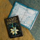 „Wicked Endeavors“, von Kamilah Cole, neben einer detailreichen Landkarte. Überlagert geometrischen Mustern in Blau und Braun.