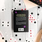 Ein Buchrücken zeigt den Text: "To do what we do, we have to have a little bit of the monster in us." Drumherum liegen Spielkarten.