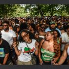 Text: "Juneteenth Annual Celebration." Eine große, fröhliche Menschenmenge feiert in einem Park unter Bäumen.