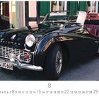 Dieses Bild zeigt einen Triumph TR3, ein glänzendes, schwarzes, klassisches Auto mit roten Sitzen und einem Koffer hinten.