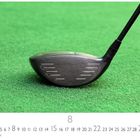 Text: "CASARES EDITION", Zahlen 1-31 im Kalenderformat, prominent die 8. Ein Golfschlägerkopf auf grünem Rasen.