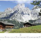 "Sulzenalm" und "8" unter rustikalen Hütten vor einer Bergkette mit grünem Hügel und blauem Himmel.