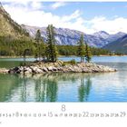 "Lake Minnewanka", Monatskalender: August. Klares Wasser, bewaldete Insel, Berge im Hintergrund.